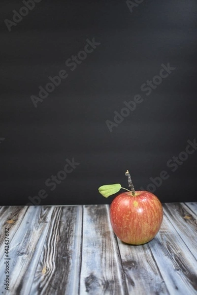 Obraz Red apple with a black background and wood table