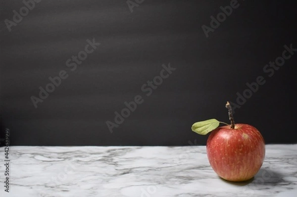 Obraz Red apple with a black background and marble table