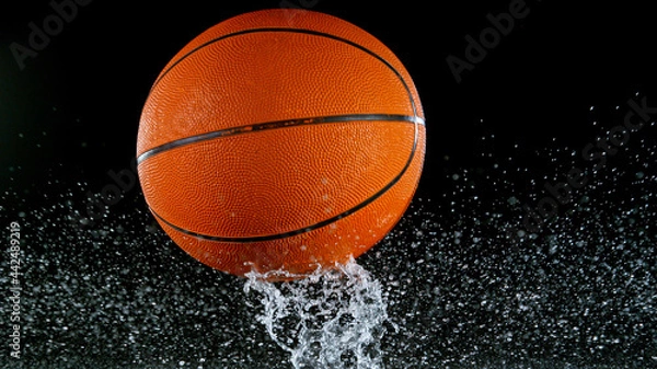 Fototapeta Falling basketball ball on water surface, black background. Top down view.