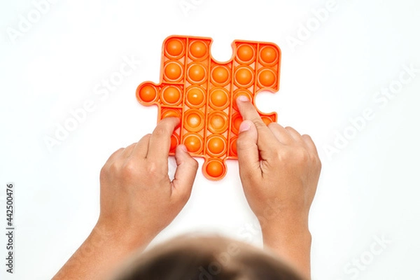Fototapeta A child with a colorful pop it game. Anti-stress. A close-up shot of children's hands playing with the popular pop It fidget toy.