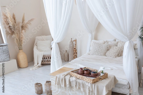 Obraz daylight through a huge panoramic window illuminates the cozy oriental interior of the room in beige colors with wicker furniture and authentic elements