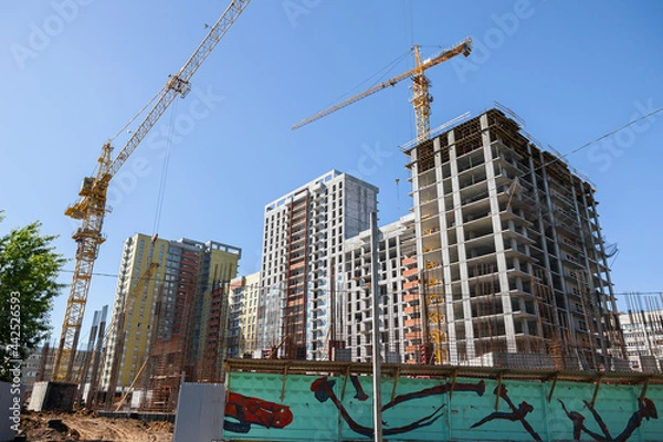 Fototapeta A high-rise building is under construction. metal and concrete structures. Yellow construction crane. A sunny summer day.