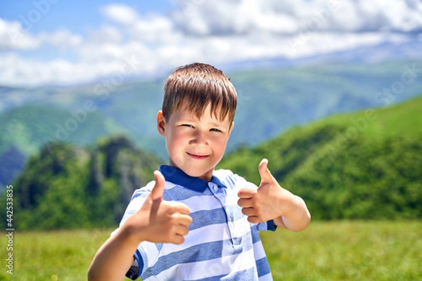 Fototapeta a funny little boy shows the class and smiles