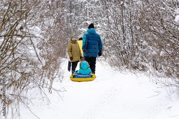 Obraz A married couple with children and friends go for a walk in the winter snow-covered forest. People, lifestyle concept
