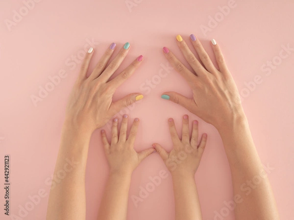 Fototapeta hands of mother and daughter with colorful nails on the pastel pink background. summer modern tropical abstract art with female hand. minimal modern background parenting idea.
