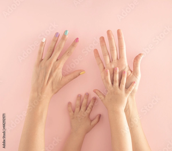Fototapeta hands of mother and daughter with colorful nails on the pastel pink background. summer modern tropical abstract art with female hand. minimal modern background parenting idea.
