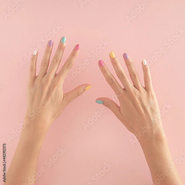 Fototapeta women hands with colorful nails on the pastel pink background. copy space.  summer modern tropical abstract art with female hand. minimal background idea with number ten