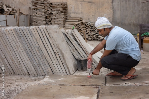 Obraz A LABOURER WORKING ON TILE WITH ELECTRIC EQUIPMENT