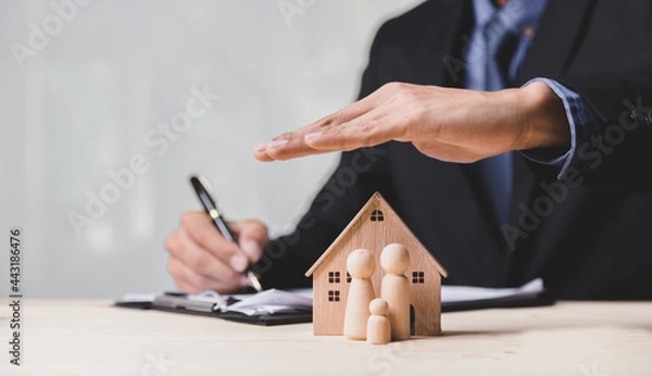 Fototapeta Insurance house, and family health live concept. The insurance agent presents the ้hands protection model that symbolize the coverage.