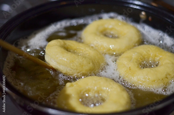 Fototapeta frying donuts in hot oil in a frying pan