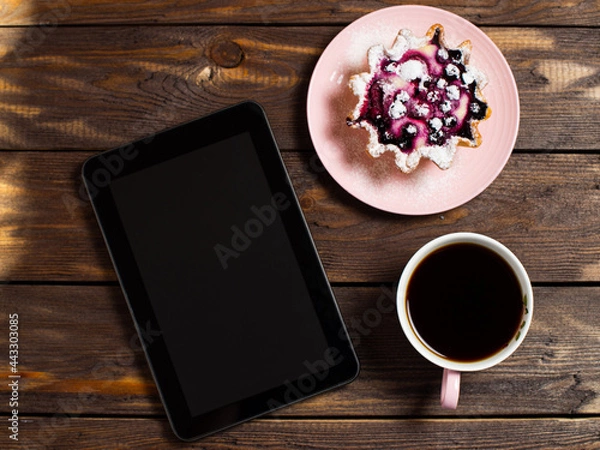 Fototapeta Flatley coffee break layout. Digital tablet gadget, black coffee in a cup and a cake basket with berries on a table from an old dark wood.