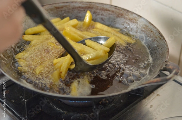 Fototapeta hand frying french fries in the frying pan