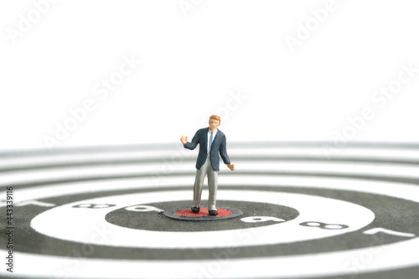 Fototapeta Miniature people toy figure photography. A shrugging businessman standing the center of dartboard. Isolated on white background. Image photo