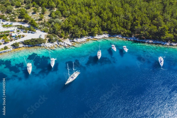 Fototapeta Aerial photo of sailing boats docked in blue bay of Fiskardo, Kefalonia island, Ionian, Greece