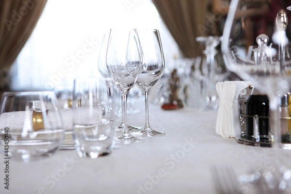 Fototapeta Festive table setting.Napkins made of cotton with brass rings.Concept of holidays.Wine glasses on table. White plates.VIP lounge. White tablecloth with textured pattern.Out of focus. 