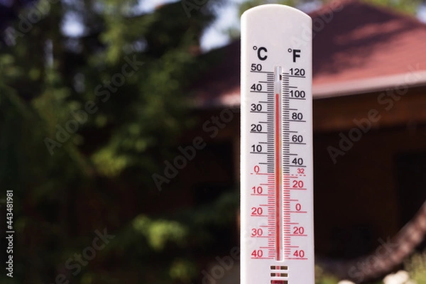 Fototapeta Thermometer on the background of a country house. An air temperature of 40 degrees is shown by a thermometer. Summer heat