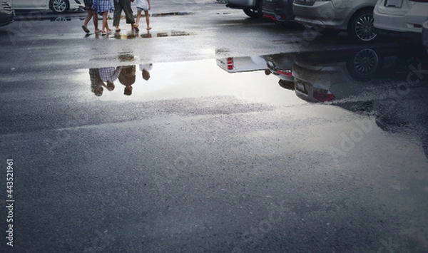 Fototapeta Wet parking spaces after hard rain fall with reflection of cars and walking people in puddle on the ground .Selective focus.