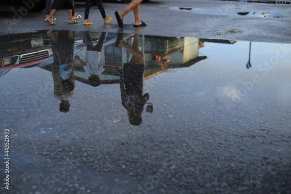 Fototapeta Wet parking spaces after hard rain fall with reflection of cars and walking people in puddle on the ground .Selective focus.