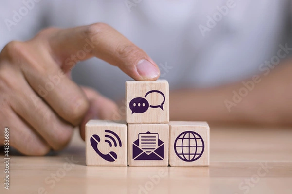 Fototapeta Human hand putting cube wood with the email, call phone, address, Chat message icons, website page contact us or email marketing ideas, customer service hotline contact us people connection