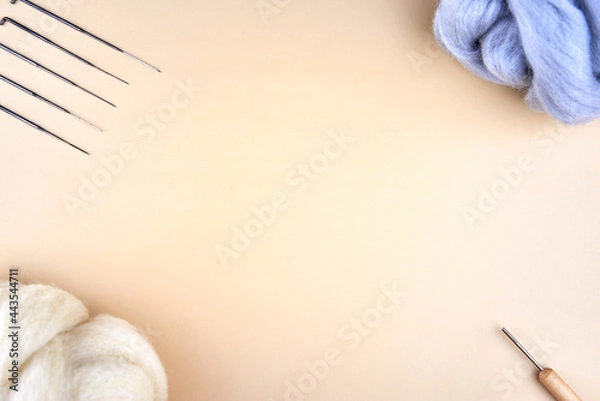 Obraz Needles and skeins of wool for felting on a beige background.