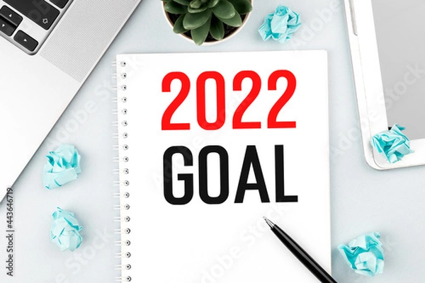 Fototapeta Text 2022 GOAL on card. Laptop, pieces of paper, pen and plant on office desk. Flat lay, top view. Planning concept.