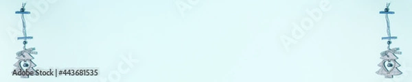 Fototapeta Banner of flat lay of wooden christmas decoration tree with heart inside it and jingle bell on blue on the left and right side. Christmas holidays concept from above with copy space