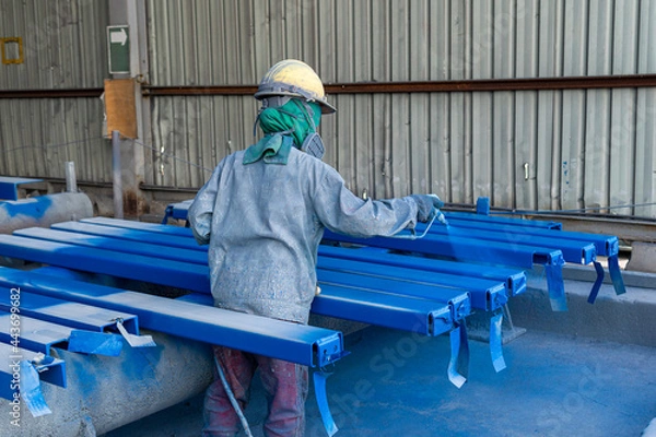 Fototapeta Painter is working to painting color top coat on steel structure with spray gun, at industrial factory.