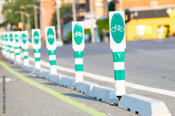 Obraz Green reflective safety barriers for bicycle lanes on the street, barriers are in selective focus with camera focusing on the first post.
