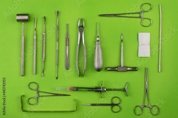 Fototapeta Set of dental instruments for teeth extraction with green background and top view