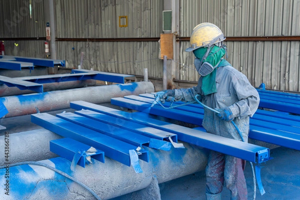 Fototapeta Painter is working to painting color top coat on steel structure with spray gun, at industrial factory.