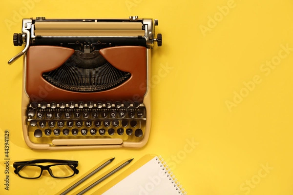Obraz Vintage typewriter, glasses and stationery on yellow background, flat lay. Space for text