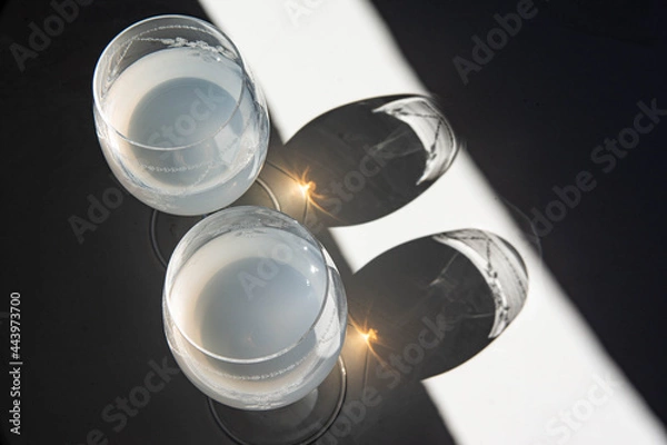 Obraz Wine glasses in the sunlight, play of reflections and shadows. Diagonals of black and white.
