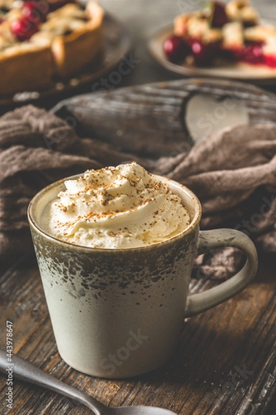 Obraz Cup of coffee with cream and cinnamon powder on an antique book on a wooden tray with fresh cherries, coffee break, vertical