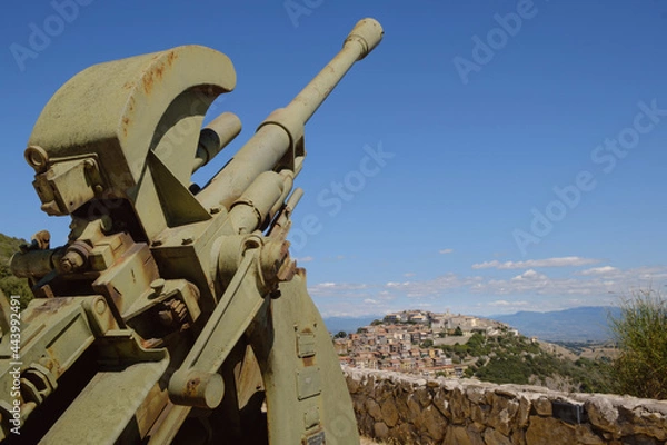 Fototapeta The ancient Sant'Oreste hamlet on the background with a world war two anti aircraft cannon in foreground near Monte Soratte fallout shelter, Sant'Oreste, Rome, Italy 