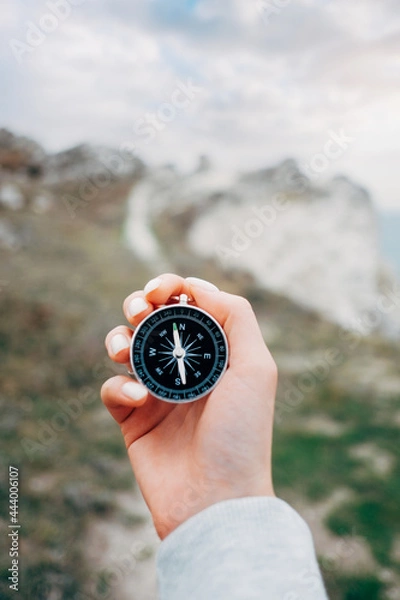 Obraz Woman hiker with a compass in her hands and a beautiful manicure in the background walking trail.