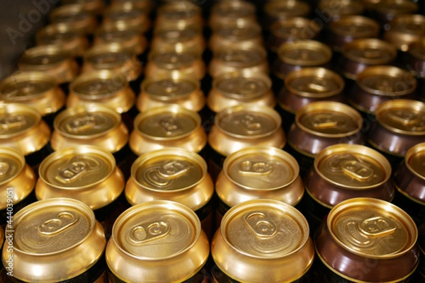 Fototapeta Many aluminum cans stand in a row on a shelf close-up. Tops of aluminum cans closeup in a row on a rack.