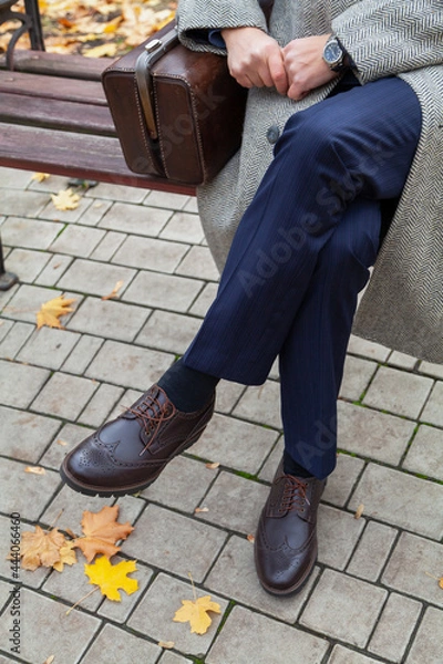 Obraz Man sits on bench in autumn  park. Near carpetbag