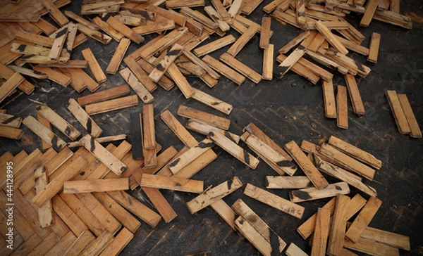 Fototapeta Old damaged parquet removal, heap of small planks at bitumen covered floor