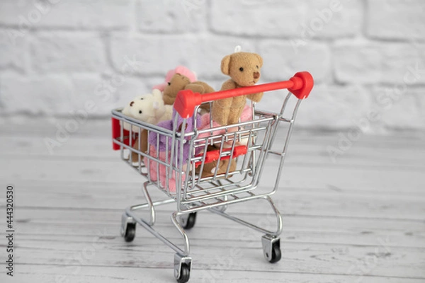 Fototapeta Many colorful toys teddy bears lie in the grocery cart. Shopping in the market. Buying gifts for birthdays and holidays