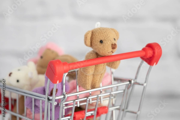 Fototapeta Many colorful toys teddy bears lie in the grocery cart. Shopping in the market. Buying gifts for birthdays and holidays