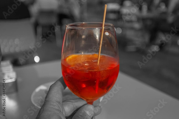 Fototapeta Close-up of hand holding a glass of spritz with color isolation effect, Vittorio Veneto, Italy
