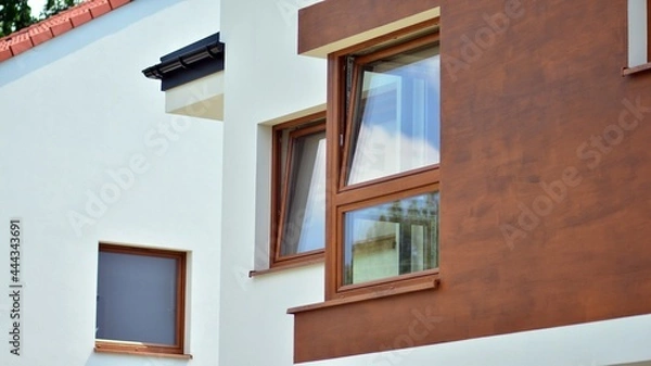 Fototapeta New single family house in a new development area.  Residential home with modern facade. Rays of the sun in the background.