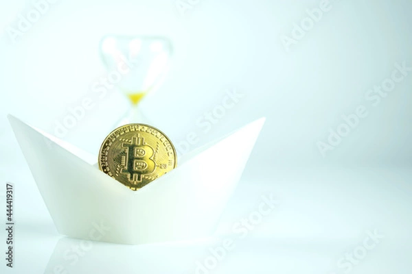 Obraz A bitcoin coin in a white ship with an hourglass. The collapse of cryptocurrencies