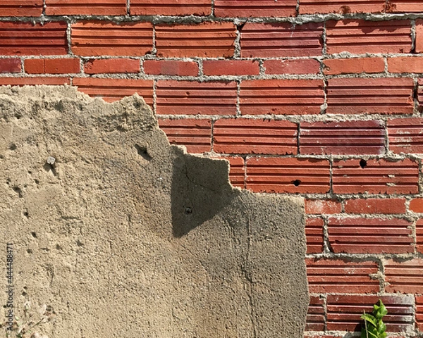 Obraz Weathered cement plaster peeling back to expose old red brick wall of abandoned building in American Midwest.