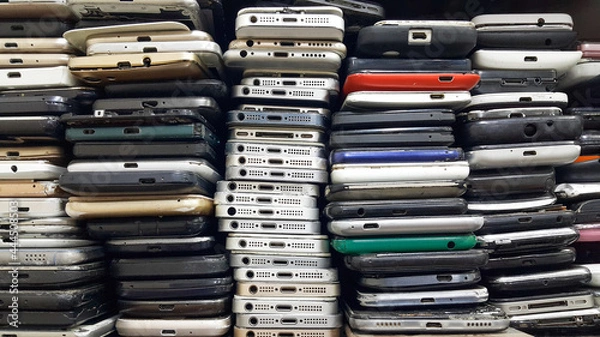 Fototapeta Background of damaged mobile phones. A bunch of broken smartphones. Used phones stacked on top of each other. Repair services and maintenance of equipment.