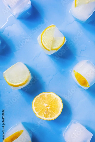 Fototapeta Modern geometric composition of the frozen slices of lemon and ice cubes on a blue background