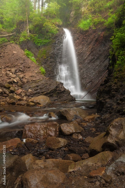 Fototapeta Waterfall in the summer forest. Colorful natural landscape with waterfall with blurry water in the mountains