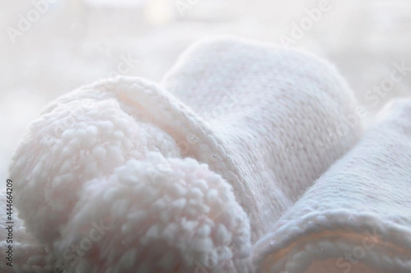 Fototapeta Rolled up knitted light pink scarf. Pastel background with knitted texture.
