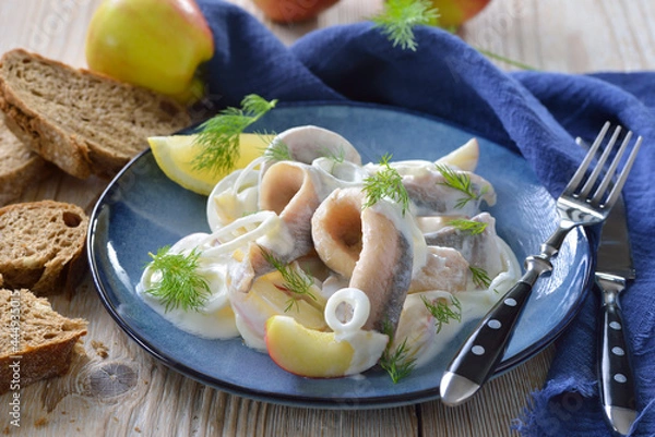 Fototapeta Marinierte Matjesfilets mit Äpfel,  Zwiebelringen und Joghurt-Sahne-Soße  - Salty herring fillets with apple slices, onion rings and yoghurt cream sauce