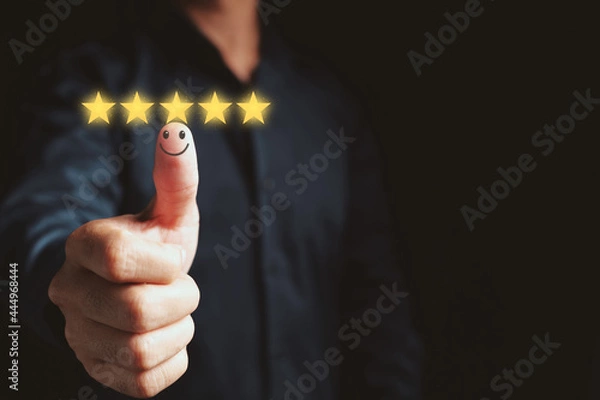 Obraz Customer satisfaction concept. Hand with thumb up Positive emotion smiley face icon and five star with copy space on black background